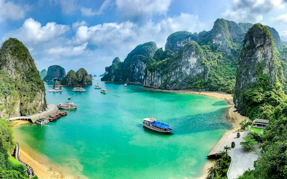 Boats on turquoise water among limestone karsts in Ha Long Bay